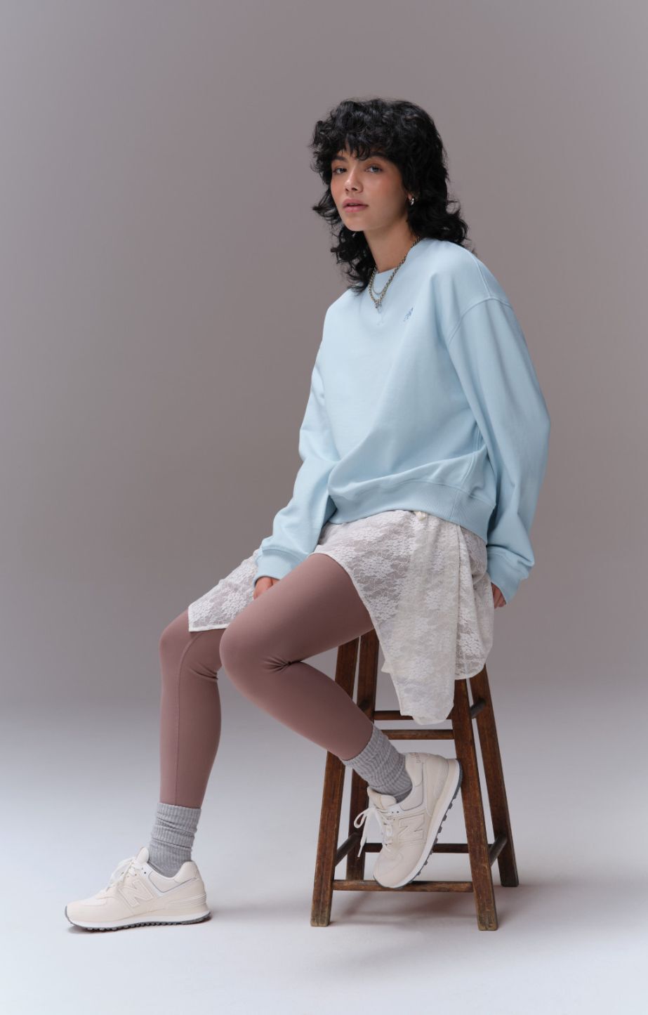 Woman sitting on a stool wearing new balance 574s